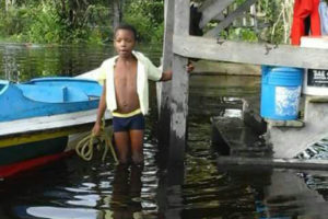 A child about to tie a boat to a post at his house.