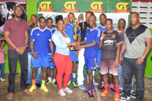 Captain of Sparta Boss Sheldon Shepherd (centre) receiving the championship trophy from Xtreme Cleaners CEO Shanae Gomes in the presence of his teammates following the 7-4 win over Tucville. Also in the picture are Director of Sport Christopher Jones (left) and Banks DIH Limited Outdoor Events Manager Mortimer Stewart (right).