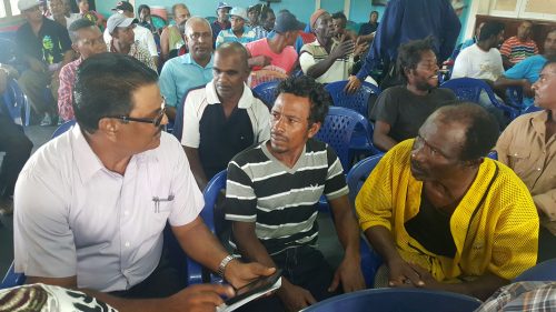 Manager of the Uitvlugt estate, Yudhisthira Mana (left) speaking to some of the workers before the start of the meeting.