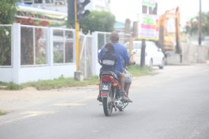 At risk: this motorcyclist placed both his and the life of the young pillion rider at risk by not wearing helmets as they rode along the East Bank Demerara (Photo by Keno George) 