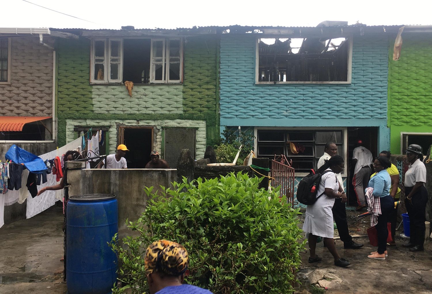 Neighbours gather around the destroyed apartment (right) trying to salvage anything that might not have been destroyed by the fire.