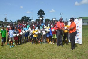 GTT PRO Allison Parker (right) hands over the quantity of footballs to secretary of Fruta Conquerors, Daniel Thomas, in the presence of the summer camp participants at the Tucville ground Tuesday.