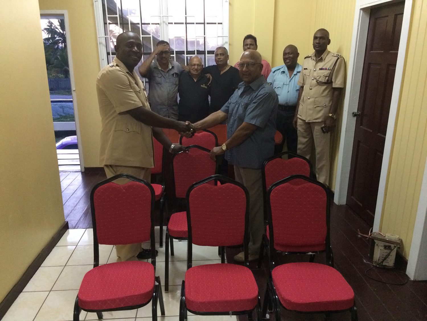 In photo,  Senior Superintendent Stanton (left) receives the furniture from Taajnauth Jadunauth in the presence of, from left (in background), Members J. Deodass, S. Mohamed, S. Shahib, M. Ali, Sgt Braithwaite and Inspector John.