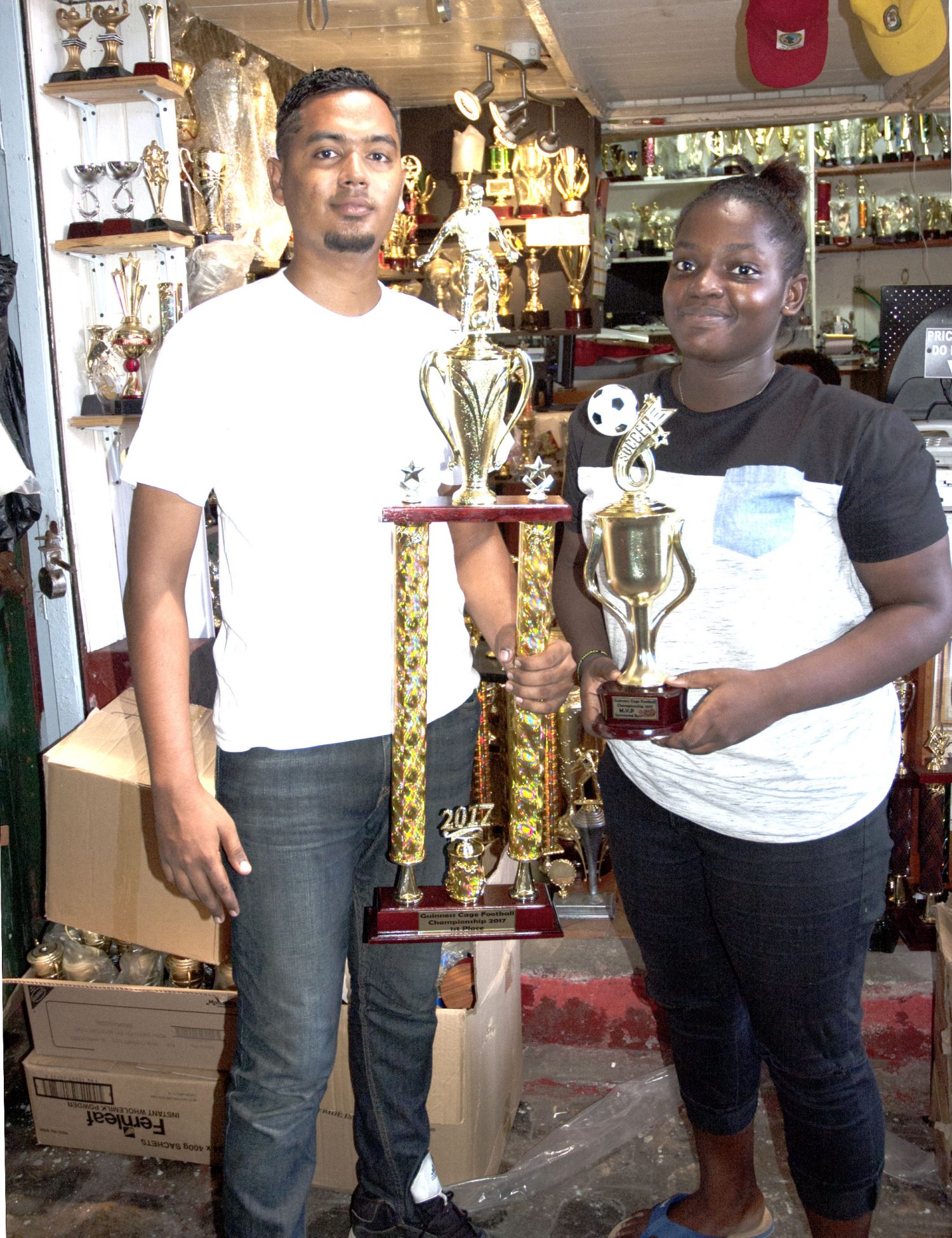 Trophy Stall continued their long standing support of local sports by donating the winner’s and fourth place trophies, as well as the most valuable player accolade, for the upcoming Guinness ‘Cage Football Championship’. Representatives Stephen Persaud and Kendra Massiah display the trophies. 
