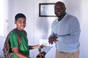 President of the Guyana Chess Federation James Bond (right) presents a trophy and cheque to Ghansham Alijohn, the second place winner of the junior category of the Rapid Chess Tournament that was held three weeks ago at the YMCA. A student of St Stanislaus College, Ghansham is fondly known as ‘Little Anand’ in chess circles, perhaps, due to his style of play. He plays chess seriously, and is one of the nation’s bright prospects for the future.
