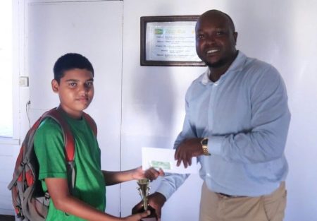 President of the Guyana Chess Federation James Bond (right) presents a trophy and cheque to Ghansham Alijohn, the second place winner of the junior category of the Rapid Chess Tournament that was held three weeks ago at the YMCA. A student of St Stanislaus College, Ghansham is fondly known as ‘Little Anand’ in chess circles, perhaps, due to his style of play. He plays chess seriously, and is one of the nation’s bright prospects for the future.
