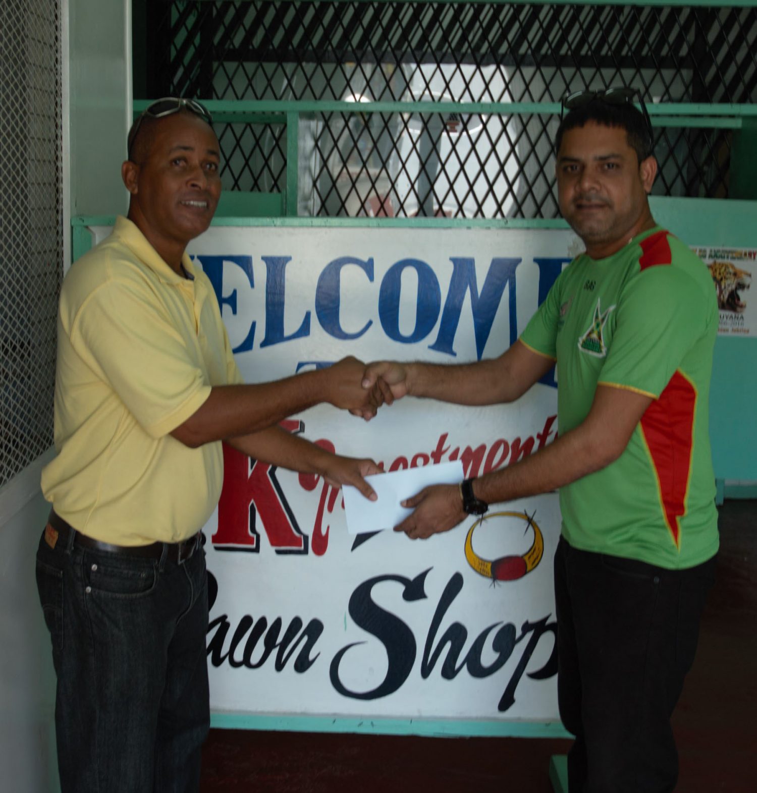 Managing Director of YK Investments & Pawn Shop Marlon Yenkana (right) hands over the sponsorship cheque to Three Peat Promotions representative Rawle Welch.