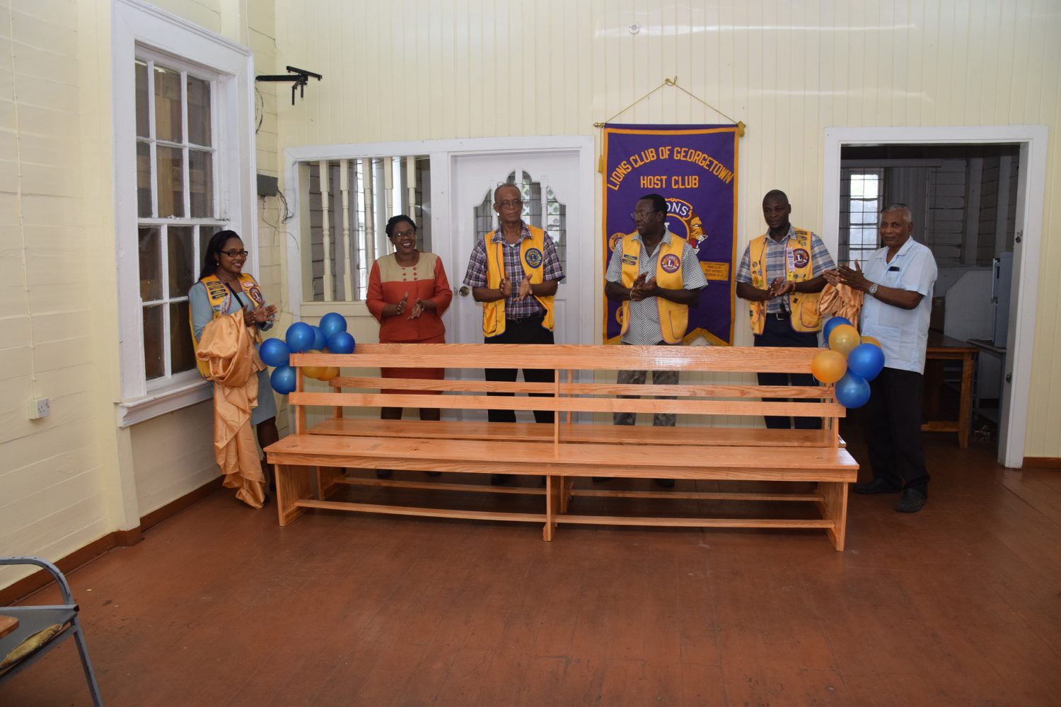 Georgetown Lions Clubs International President Lance Kennedy and his club members with Guyana Post Office Corporation Area Manager, Donette Semple along with a customer unveiling the benches.

