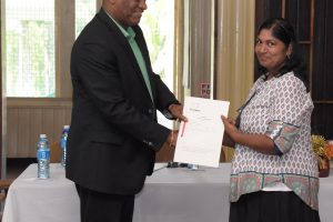 Bibi Ameena a receiving her title from Minister of State, Joseph Harmon (Ministry of the Presidency photo)