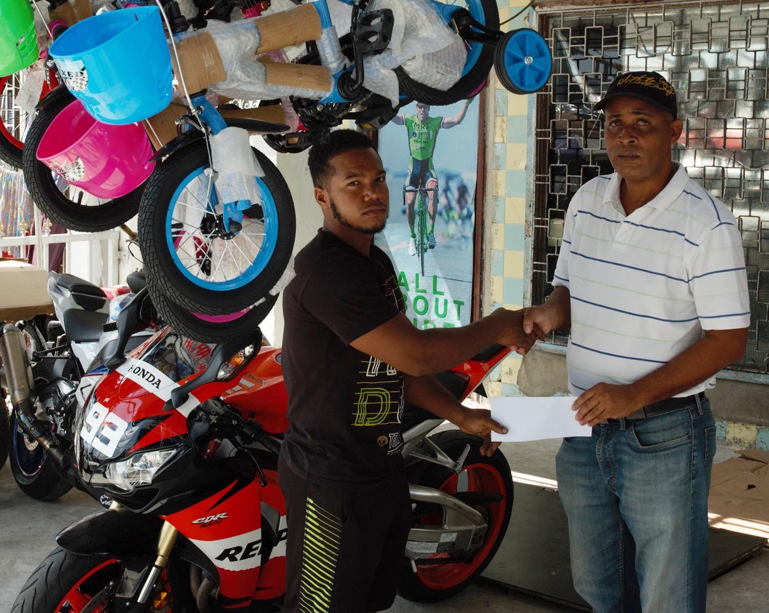 Three Peat Promotions Rawle Welch (right) collecting the sponsorship cheque from Jamal Bentley of the Bike Shop at the entity’s Robb Street location
