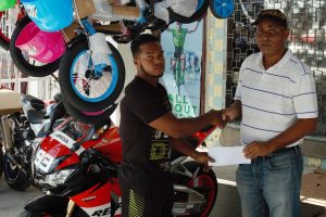 Three Peat Promotions Rawle Welch (right) collecting the sponsorship cheque from Jamal Bentley of the Bike Shop at the entity’s Robb Street location