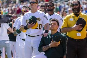 Oakland Athletics catcher Bruce Maxwell (13) kneels during the national anthem as right fielder Mark Canha (20) places his hand on his shoulder before a game against the Texas Rangers at Oakland Coliseum. Mandatory Credit: John Hefti-USA TODAY Sports