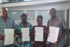 Revoked leases: Rice farmers (from left) Rawle Miller, Rupert Blackman, Doreen Monah and Philip Alexander Johnson holding up their leases last week.