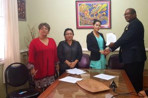 Representatives of the Amerindian Peoples’ Association Jean La Rose (at left) and Laura George (second, from left) with the first recipient of the Clarence A. F. Hughes Scholarship for Indigenous students pursuing the LLB programme, Paula Gomes (centre), as she receives documentation from attorney Nigel Hughes. (Mariah Lall photo)    