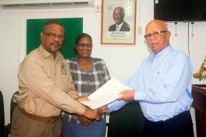 Clifford B. Reis Chairman/Managing Director of Banks DIH Limited (right) presents a copy of the Agreement to  Charles Ogle, Chief Labour Officer in the presence of a Ministry of Social Protection official. (Banks DIH photo) 