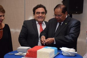 Prime Minister Moses Nagamootoo cutting the cake.  Ambassador of Chile, Claudio Rojas Rachel is next to him
