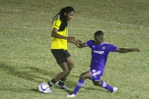 Jermaine Grandison (right) of GPF  about to tackle Western Tigers Jamal Pedro during their Corona Invitational Football Championship semifinal at the GFC ground Sunday night. (Orlando Charles photo)