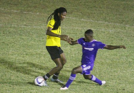 Jermaine Grandison (right) of GPF  about to tackle Western Tigers Jamal Pedro during their Corona Invitational Football Championship semifinal at the GFC ground Sunday night. (Orlando Charles photo)