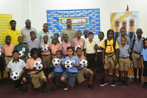 Representatives from the participating schools in the Courts Pee Wee U11 Primary School football tournament posing with members of the launch party inclusive of Petra Organization Director Troy Mendonca (third from left), Marketing Director of Courts Guyana Incorporated Pernell, Cummings (centre) and Banks DIH Malta Supreme brand manager Clayton McKenzie (right).
