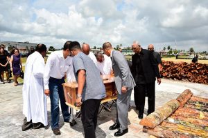 President David Granger (right) and others preparing to place the coffin on the pyre. (Ministry of the Presidency photo)