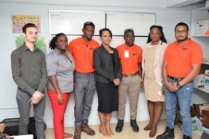 Exxon’s Community Relations and Communications Manager Nicholas Yearwood (left), EDO Country Manager Kerri Gravesande (centre), GTI Principal Renita Crandon-Duncan (second from right) pose with the trainees. (DPI photo)