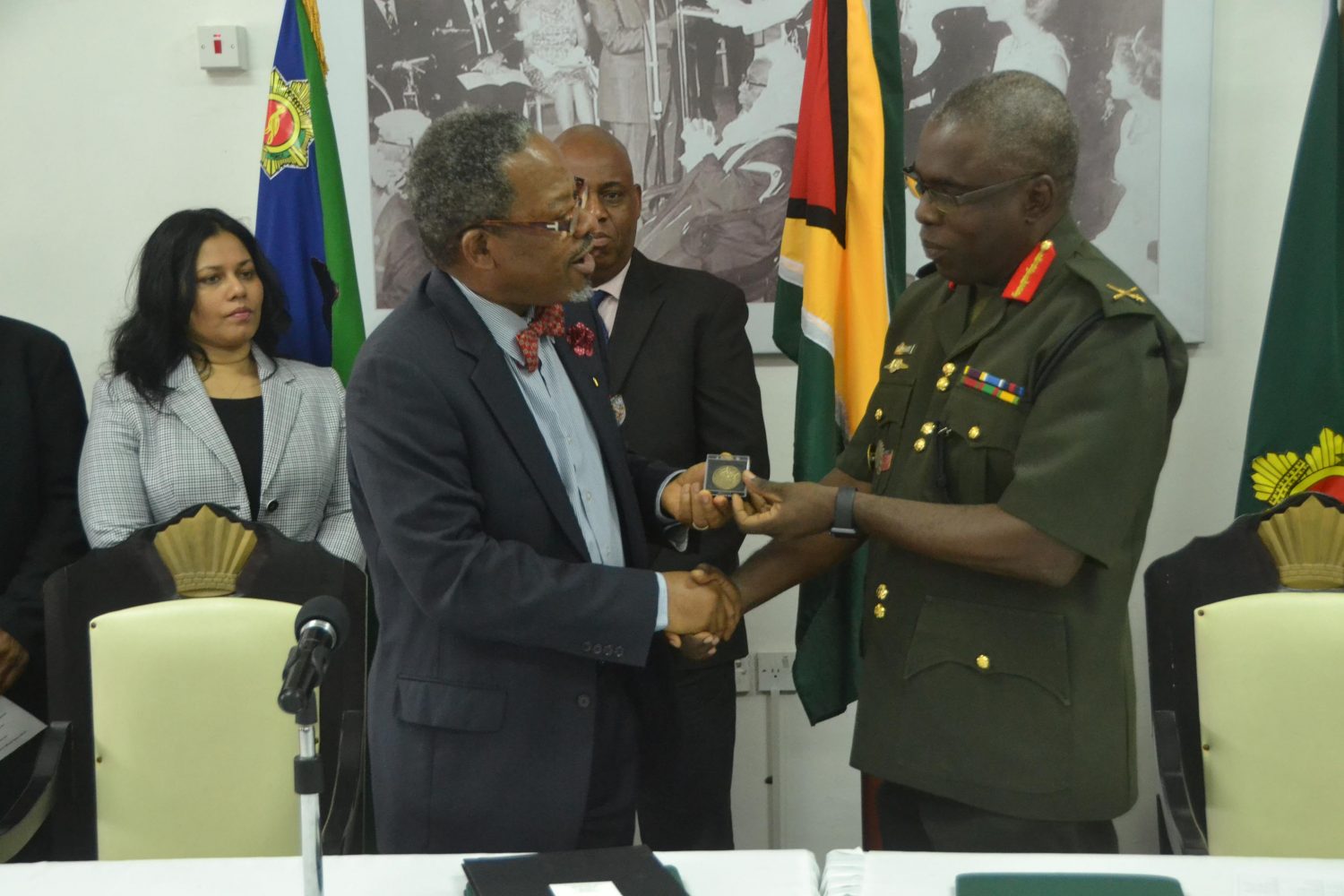 Brigadier Patrick West (right) hands over a ceremonial “coin” to University of Guyana Vice Chancellor, Ivelaw Griffith (DPI photo)
