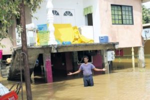 Gopee Ramsewak of Logwood Trace, Mafeking, Mayaro stands in flood waters at the front of his home yesterday.