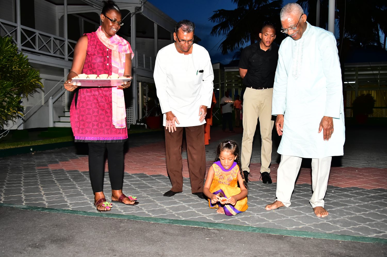 President Granger assists his grand daughter, Farrah with placing the first diya in the driveway of State House.
