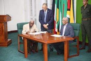 Retired Justice James Patterson signing his instrument of appointment in the presence of President David Granger
