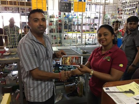 Yogeshwar Ragbeer hands over his company’s sponsorship along with some flyers to Tina Morris for the GMR&SC International Race of Champions in November.