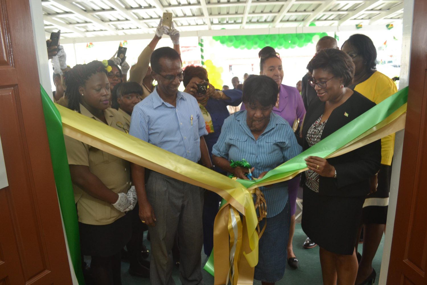  Pensioners and Minister of Public Telecommunication, Cathy Hughes (right) cutting the ribbon to declare the Kitty Post Office opened. (DPI photo)