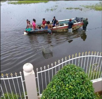 A fishing boat carrying stranded villagers is pushed along the La Fortune/Woodland Road in South Oropouche on Friday. Photo: Shawn Surujbally.