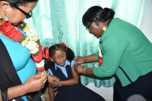 Nine-year-old Shoneta Jeffrey takes the first HPV Vaccine, administered by Minister within the Ministry of Public Health Dr. Karen Cummings. (DPI photo)