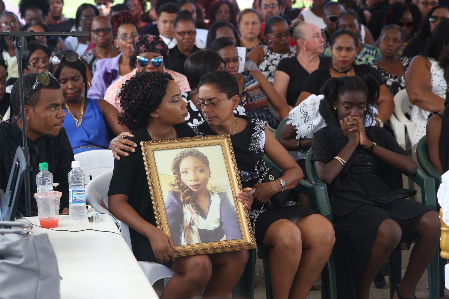 Kessandra Blackman, Kescia Barnche’s twin sister, being comforted as she held on to a portrait of her murdered sibling, who was laid to rest yesterday. (Photo by Keno George)