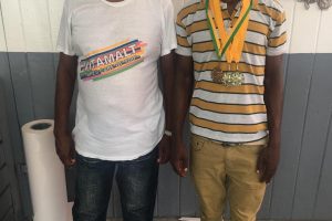 Rising Star Balram Narine (right), displays his spoils [two gold medals and a bronze medal] from the ongoing National Schools, Cycling, Swimming and Track and Field Championships, alongside coach Randolph Roberts.
