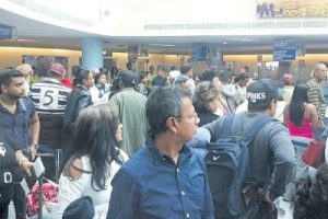 Passengers mill about the immigration section of the Piarco Airport yesterday.