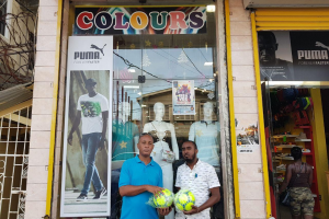 Three Peat Promotions Co-Director Rawle Welch (left) receives a donation of footballs for the playoff round of the Guinness ‘Greatest of the Streets’ Georgetown zone, from Colours Boutique representative Troy Lamazon.
