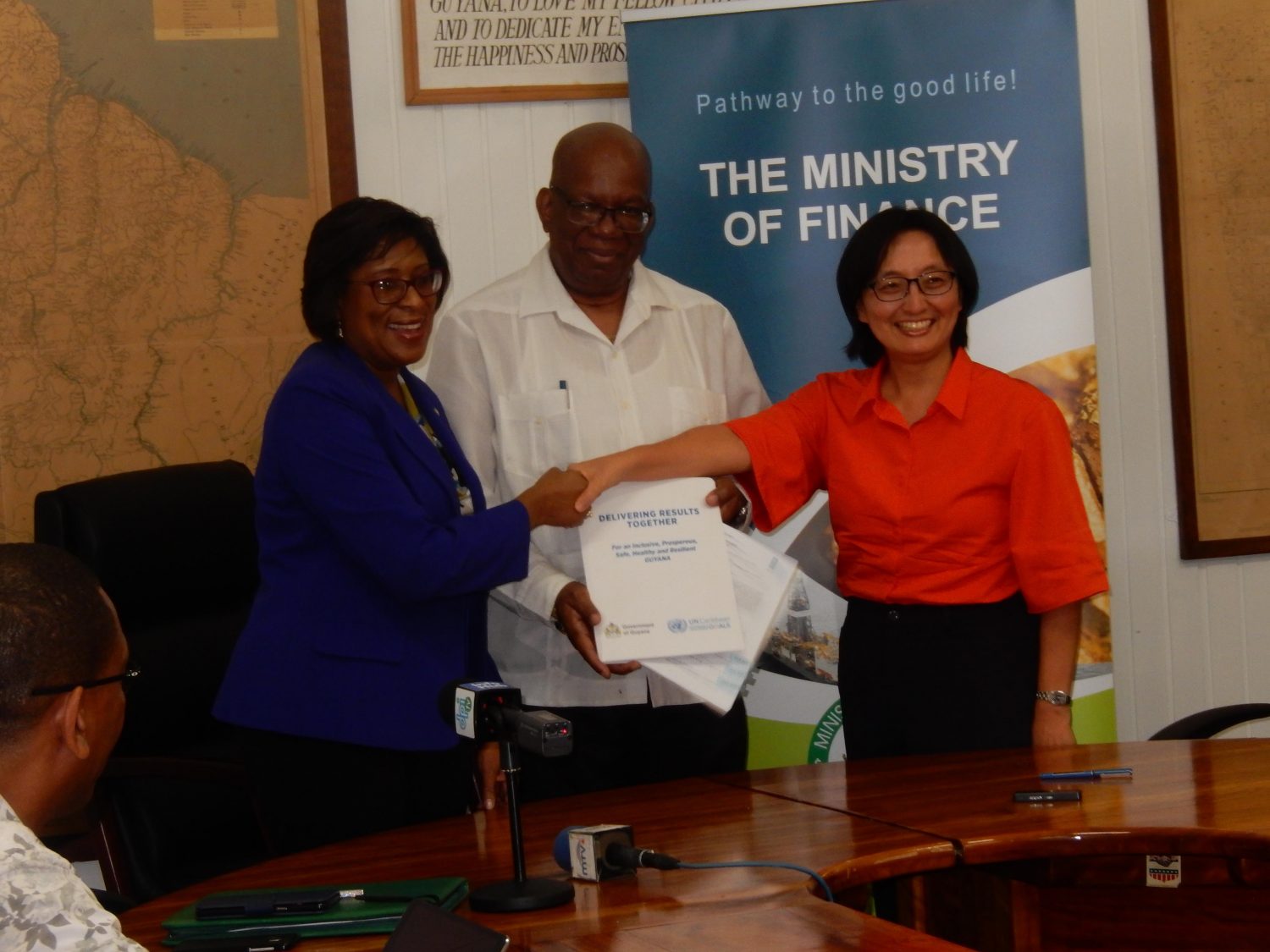 Minister of Public Telecommunications, Catherine Hughes (left) shaking hands with  UNDP Resident Representative, Mikiko Tanaka on the deal. Finance Minister Winston Jordan is at centre.  (Ministry of Public Telecommunications photo)
