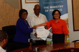 Minister of Public Telecommunications, Catherine Hughes (left) shaking hands with  UNDP Resident Representative, Mikiko Tanaka on the deal. Finance Minister Winston Jordan is at centre.  (Ministry of Public Telecommunications photo)