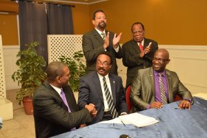 Attorney General and Minister of Legal Affairs Basil Williams (second from left) shakes hands with Chairman of the LCA, Courtney Wynter as UCC Group Executive Dr. Winston Adams (seated), UCC Executive Chancellor and Interim President Professor Dennis Gayle and Advisor Dr. Trevor Hamilton (standing) look on. This was at the signing in January this year. (GINA photo)