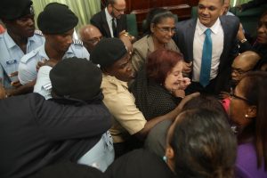 PPP/C MP Juan Edghill (right in spectacles) being shielded by fellow MPs as the police attempted to evict him from Parliament Chambers yesterday.  PPP/C Chief Whip Gail Teixeira is at centre. (Keno George photo)