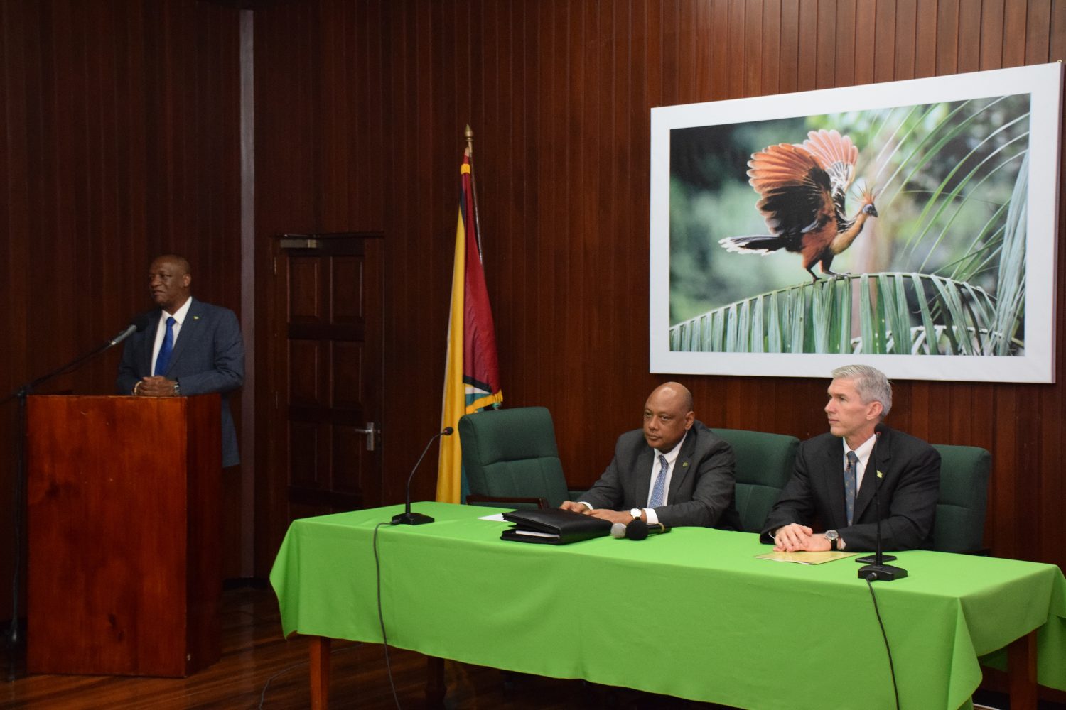 Minister of State Joseph Harmon at the rostrum speaking at yesterday’s unveiling of the ExxonMobil petroleum agreement. Seated at the head table from left are Minister of Natural Resources Raphael Trotman and ExxonMobil’s country head, Rod Henson. (Ministry of the Presidency photo)