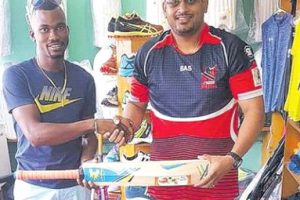 Vishal ‘Nick’ Ramnarine with one of his sponsored cricketers Travis Blyden at his store in Debe.