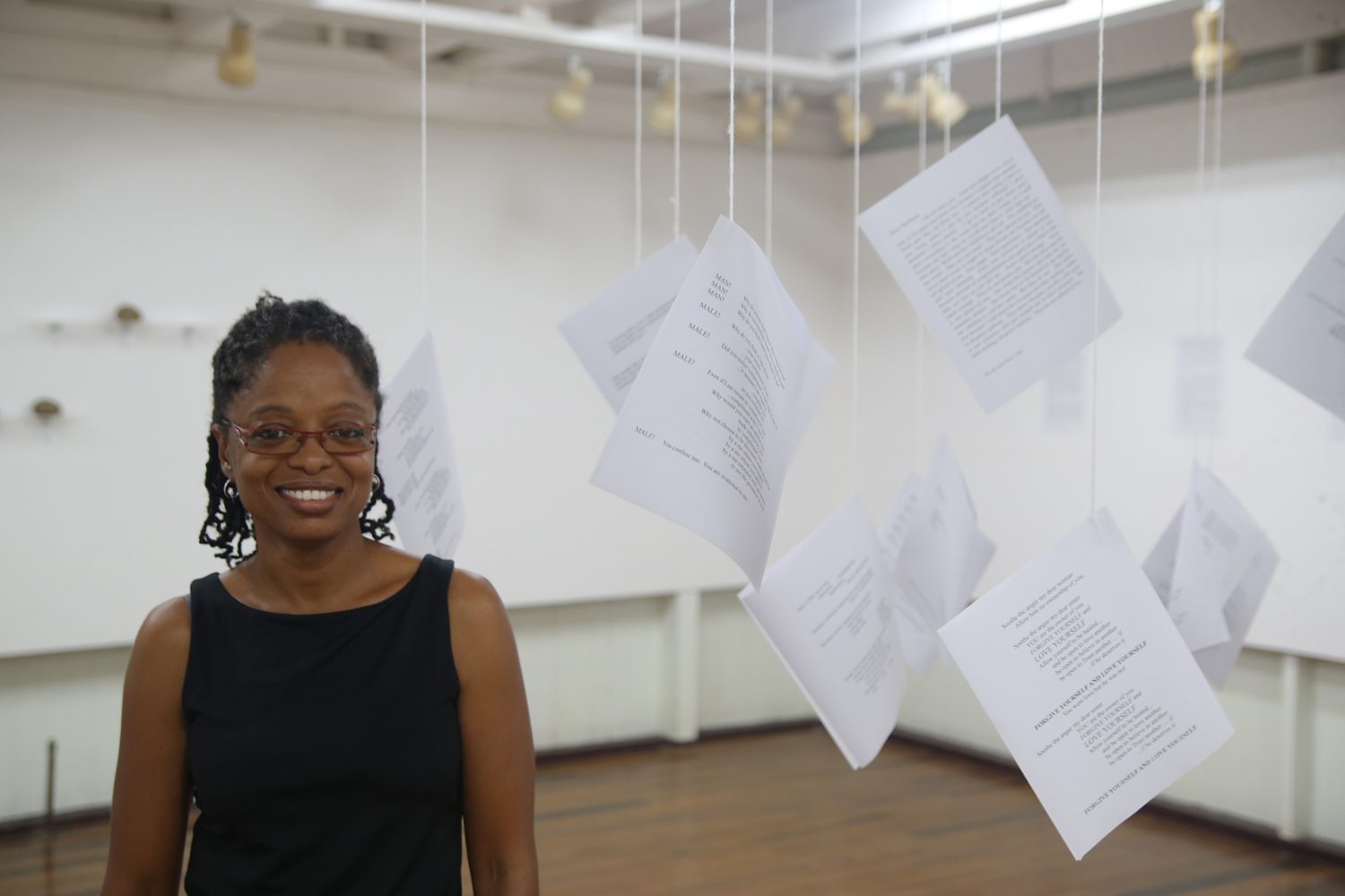 Artist Akima McPherson stands among the suspended text that form part of her exhibition.