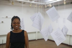 Artist Akima McPherson stands among the suspended text that form part of her exhibition.