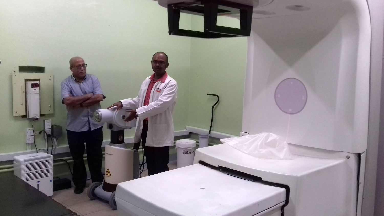  Dr. Sayan Chakraborty explains how the brachytherapy machine works, while Dr. Syed Ghazi looks on.