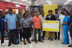 A Courts official (holding cheque) poses with some of the winners 