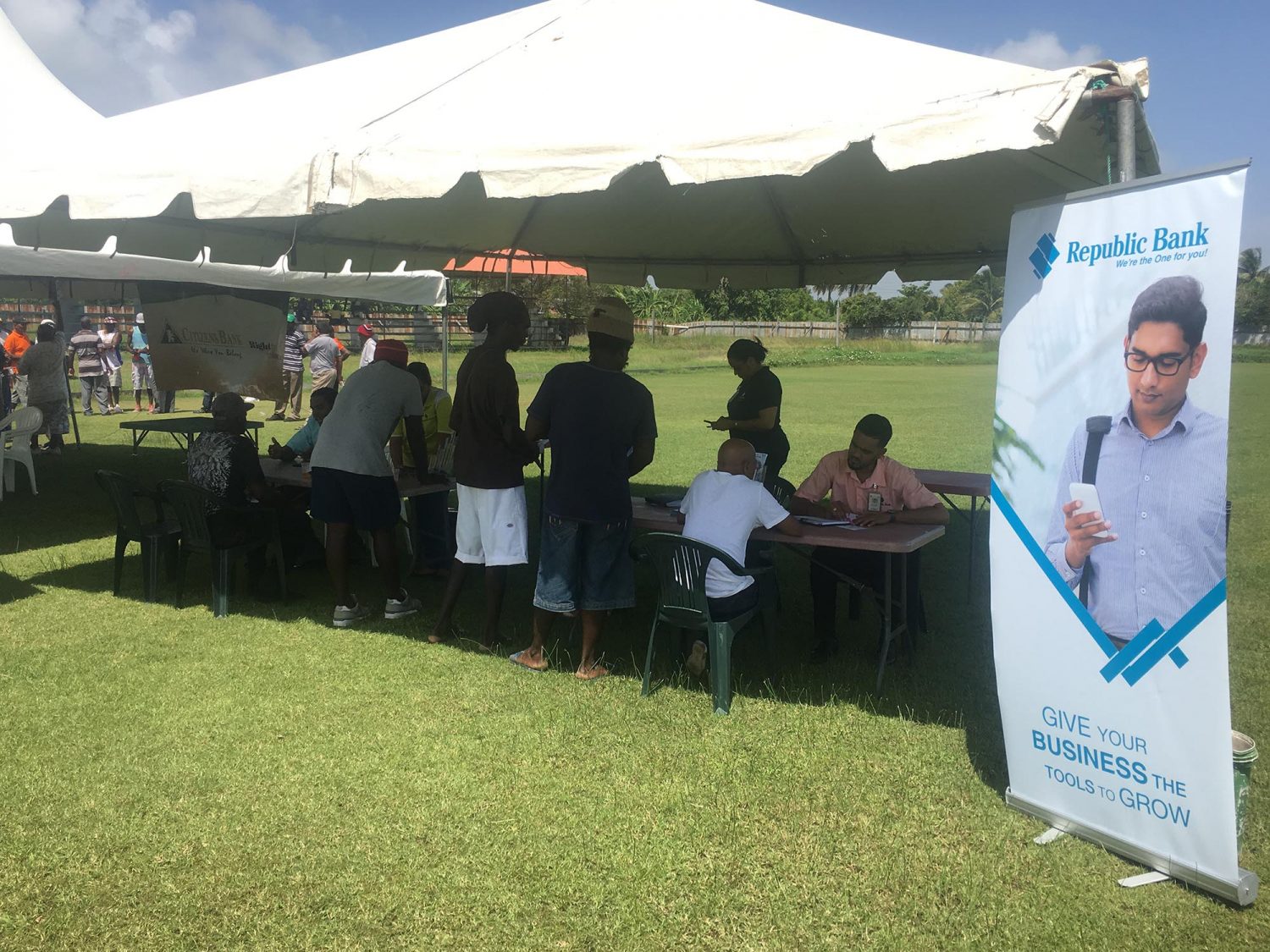 Some workers receiving information from the Republic Bank booth yesterday morning at the Enmore Community Centre ground. 