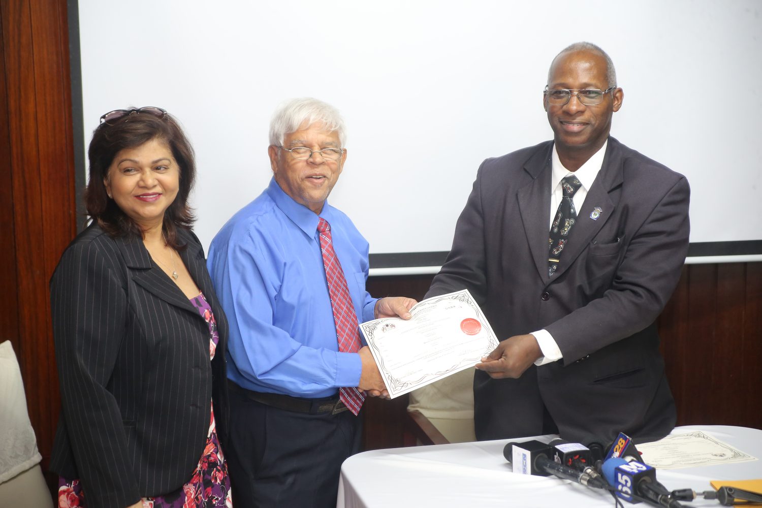 CN Sharma and his wife Savitrie Sharma receiving their radio licence from Chairman of the Guyana National Broadcasting Authority Leslie Sobers 