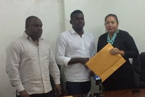 Chairman of the Parking Meter Renegotiation Committee Akeem Peter (centre) hands over the final report to Mayor Patricia Chase-Green. At left is Town Clerk Royston King.